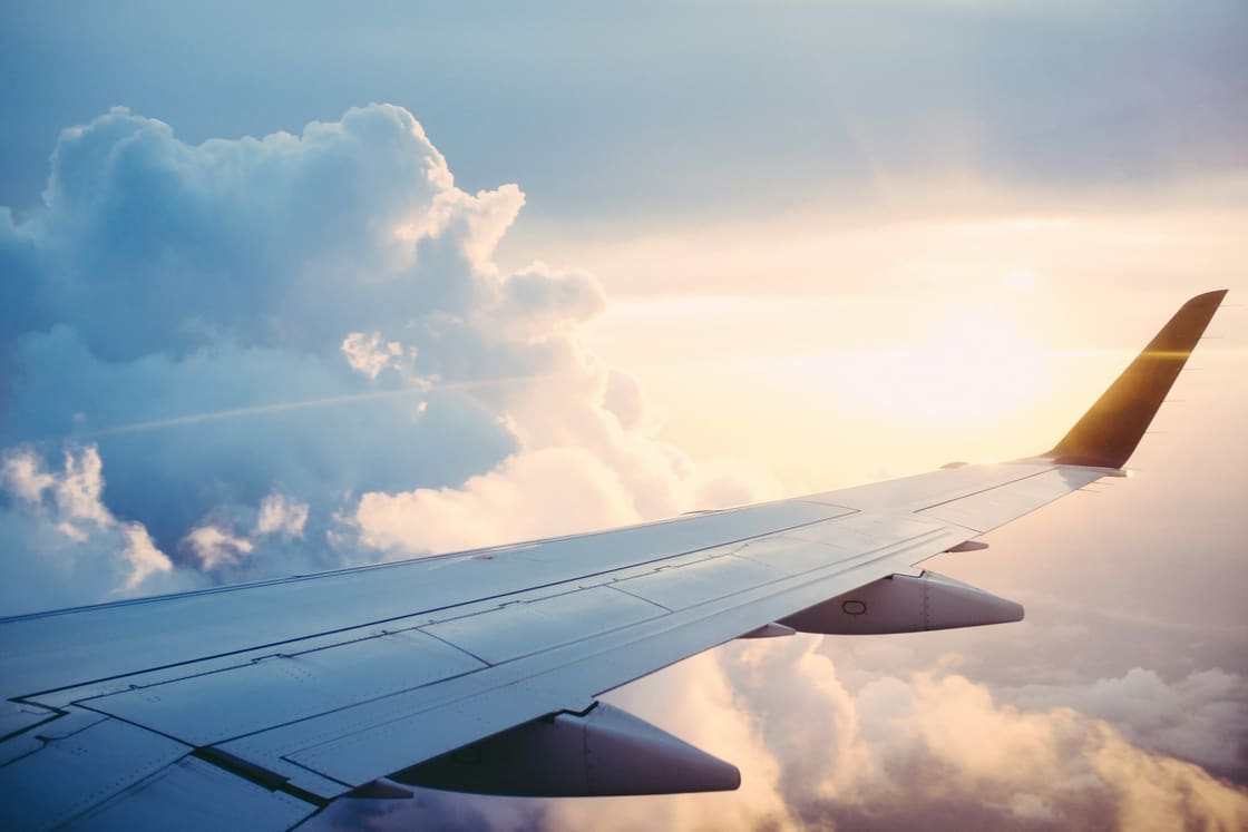 View over an airplane wing above clouds at sunset