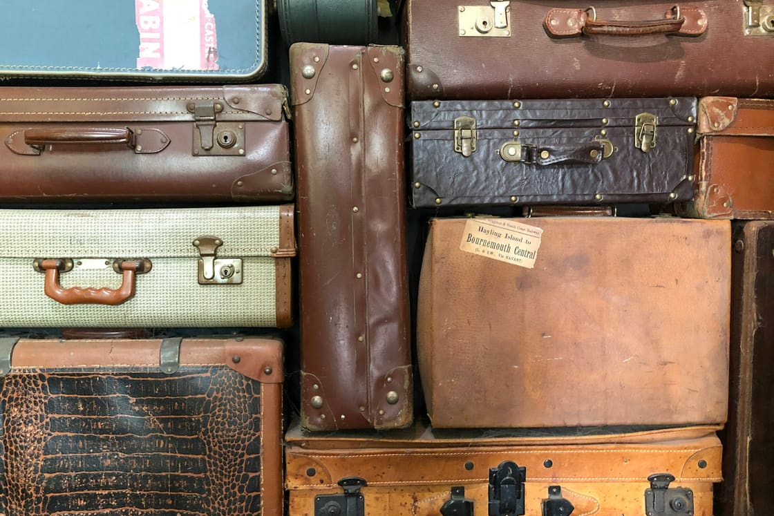 Wall of stacked vintage leather suitcases with old travel labels