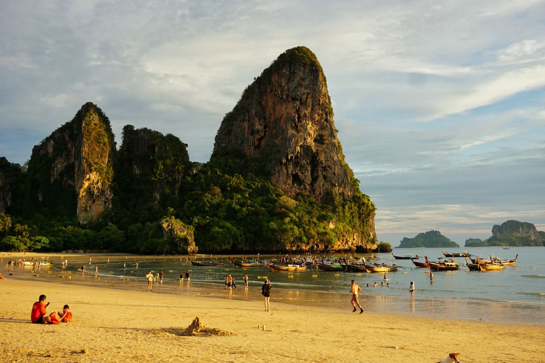 Longtail boats and towering limestone cliffs above Railay Beach, Krabi, at golden hour