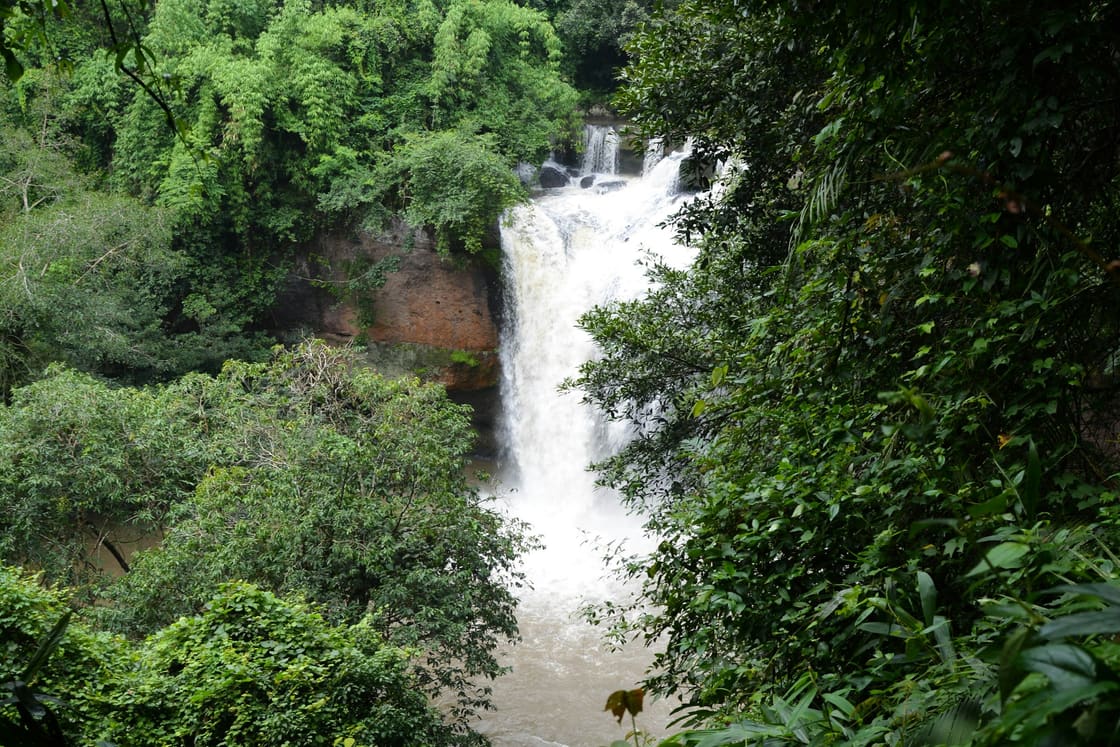 A waterfall pouring through dense green jungle in a Thai national park
