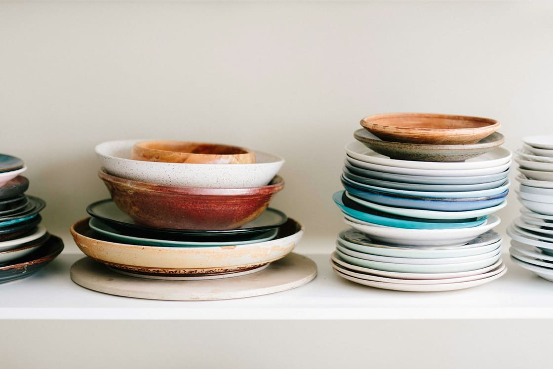 Stacks of colourful handmade ceramic plates and bowls on a shelf