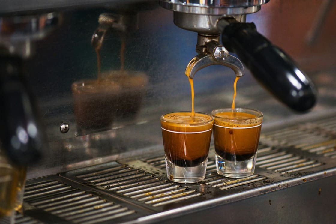 Two espresso shots being pulled into glasses on an espresso machine