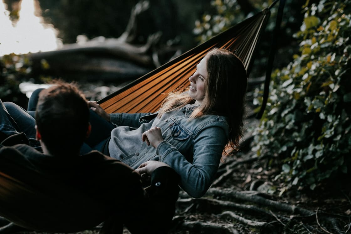 Couple laughing together in a hammock in golden evening light