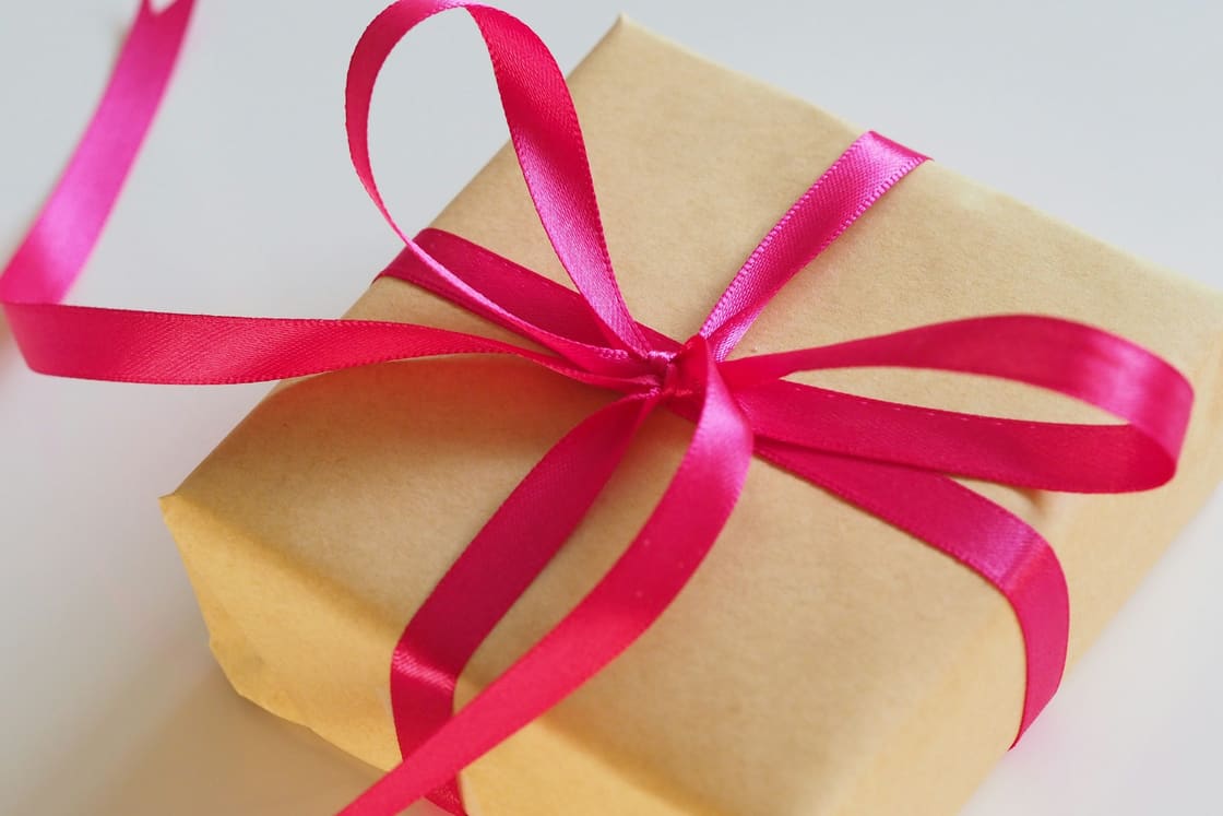 Gift wrapped in kraft paper and tied with a bright pink satin ribbon